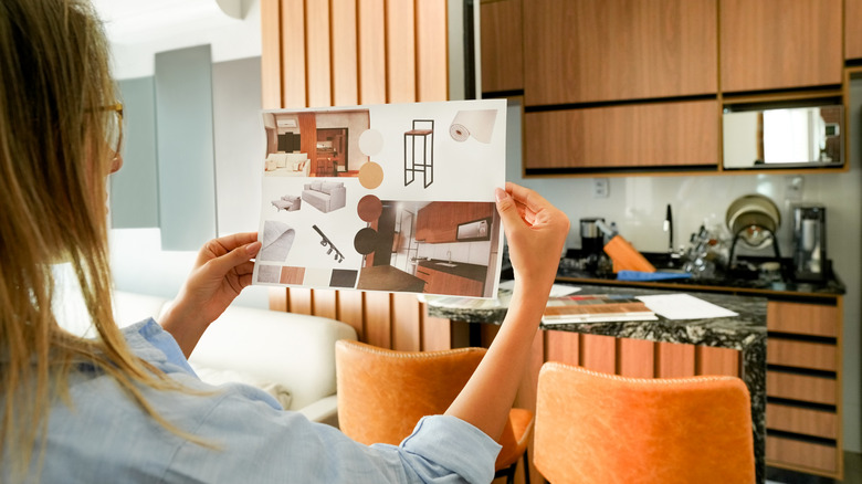 A woman holding up a design scheme for her kitchen