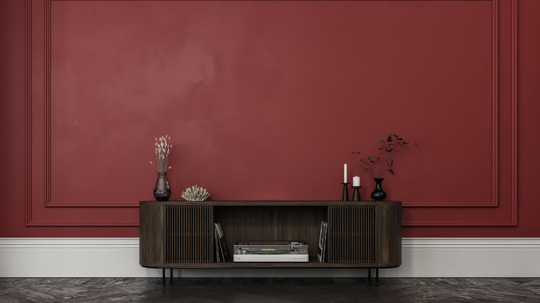 A low cabinet against a deep red wall.