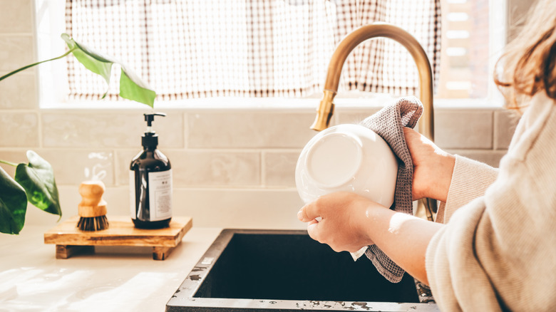 Person washing dishes with a gold faucet