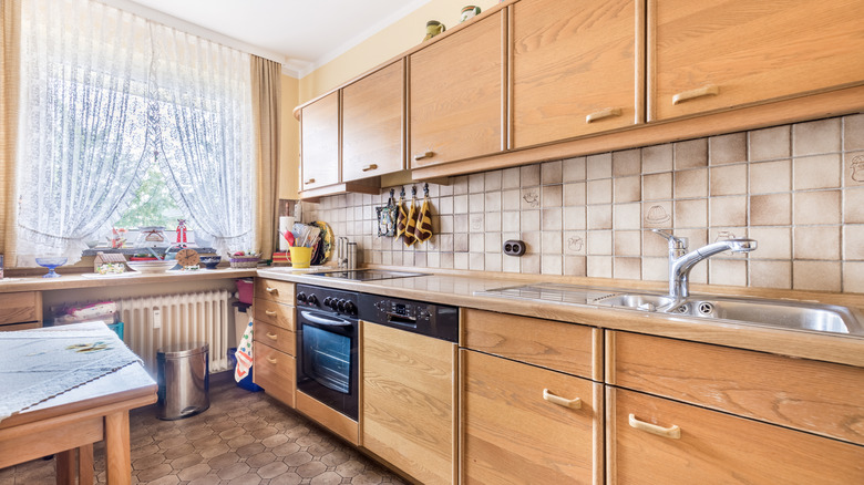 Outdated kitchen with wood cabinets and tile backsplash