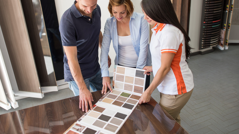 A couple chooses colors from a flooring catalog