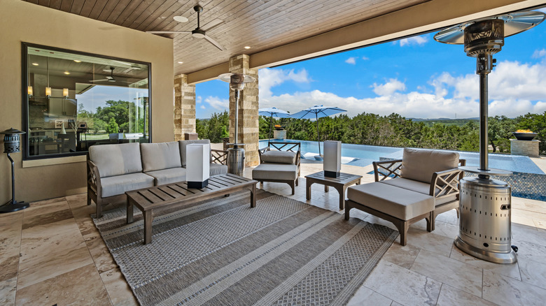 Shaded outdoor patio with light stamped concrete covered by outdoor rug, matching patio furniture