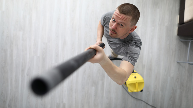 Man pointing vacuum at ceiling