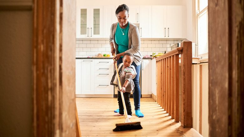 Woman and child sweeping kitchen