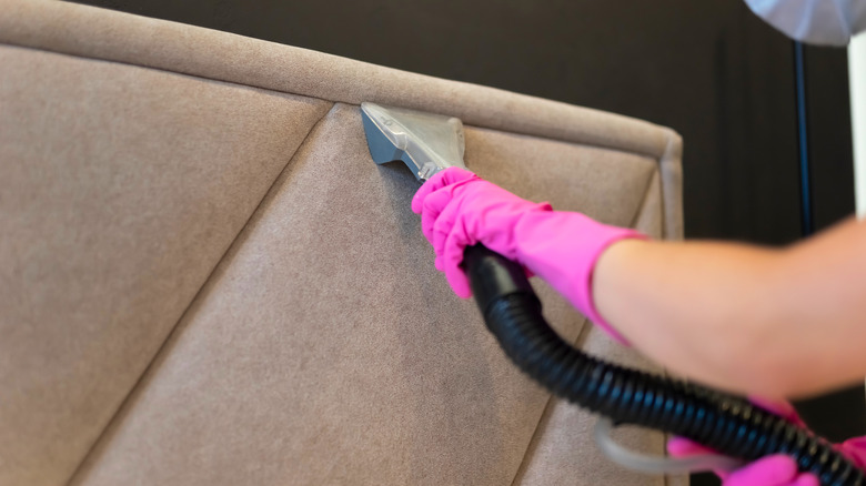 Person vacuuming headboard