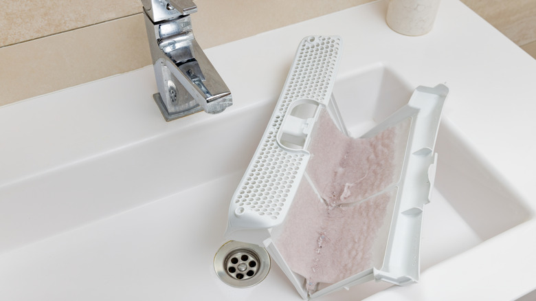 Dryer lint trap full of lint sitting in a white sink