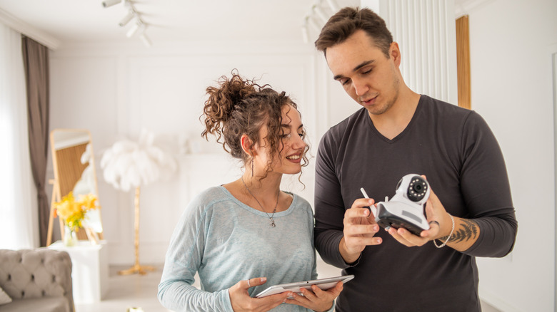 A couple installs a home security camera indoors