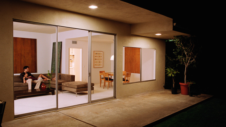 modern home with outdoor lights and glass doors showing couple on the sofa in the living room