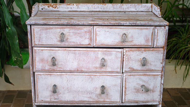 An old cabinet that has white uneven finish