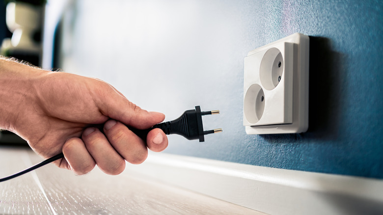 A person plugs a cord into the wall