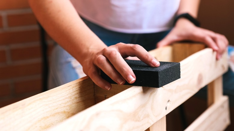 person sanding wood pallet