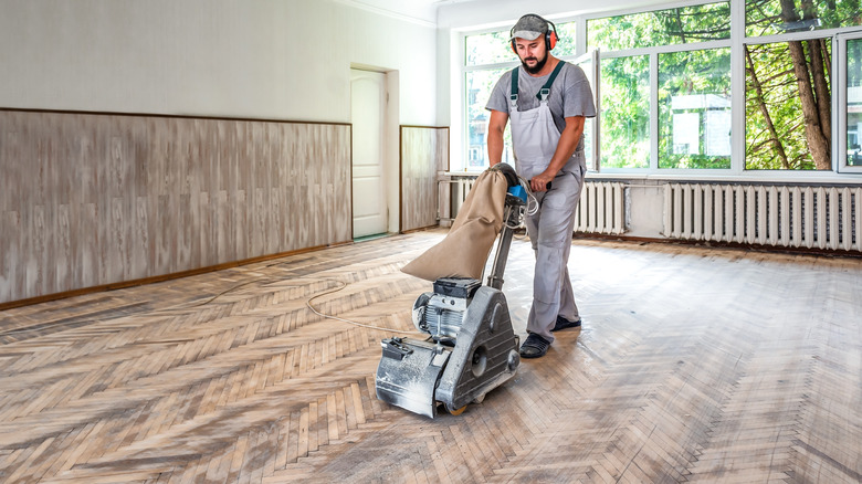 A person sanding an old wooden floor