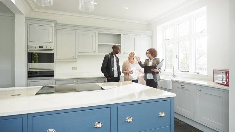 A real estate agent shows a couple a large kitchen