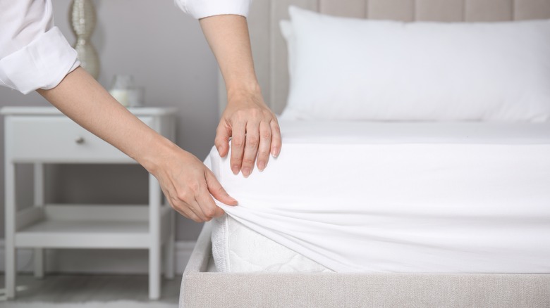 Woman putting sheets on bed