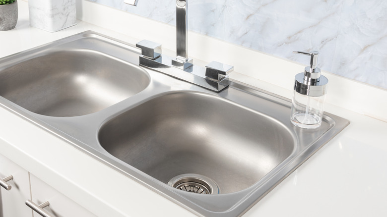 Two gray kitchen sinks have a soap dispenser next to them