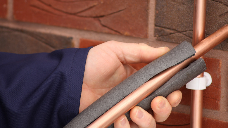 A plumber installing pipe insulation