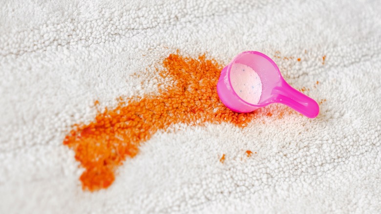 stain and bleach measuring cup on white carpet