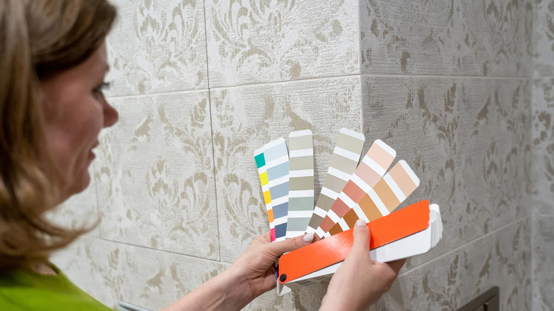 Woman looking at paint color cards in bathroom