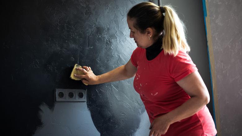 Woman sponge painting her wall black