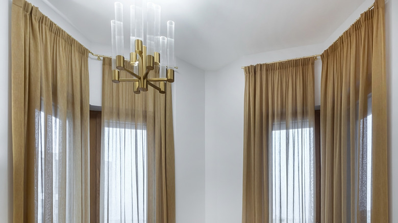 Gold curtains hang from window treatment hardware in a white-walled room