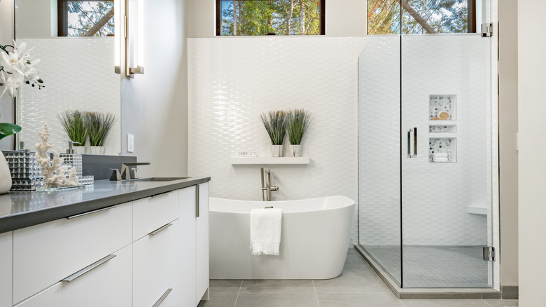 A smaller freestanding tub tucked into the corner of a bathroom between the shower and the vanity