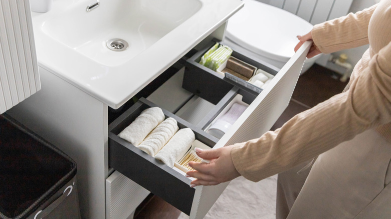 Hands organizing an open bathroom drawer