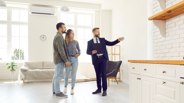 Real estate agent showing home with white neutral wall paint and decor to potential buyers