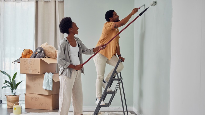 couple painting walls mint green