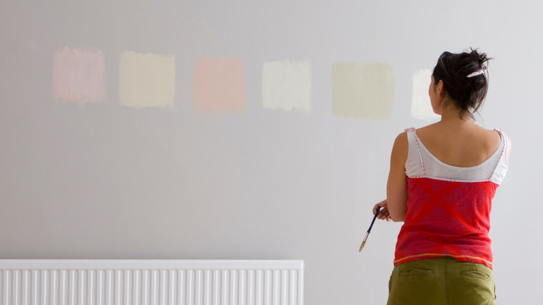 woman sampling paint on wall