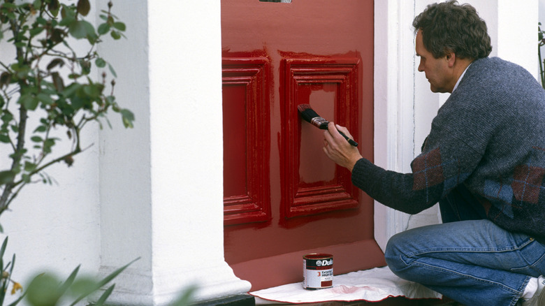 man painting his front door red