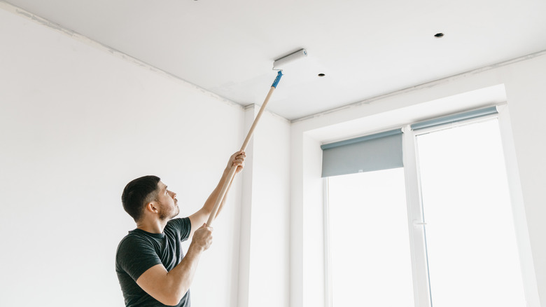 Person paint rolling a ceiling