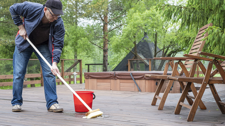 Man cleans his patio with broom