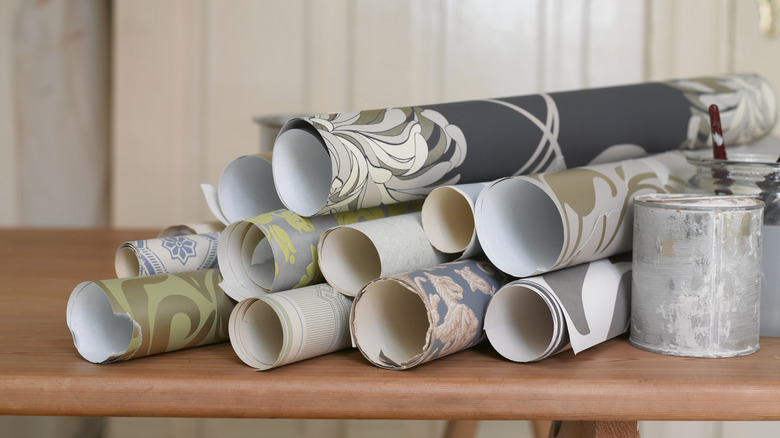 Rolls of wallpaper rest on a table