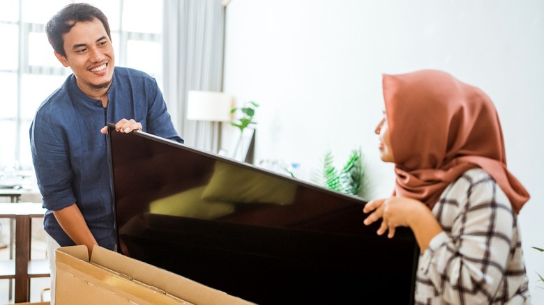 man and woman unboxing TV