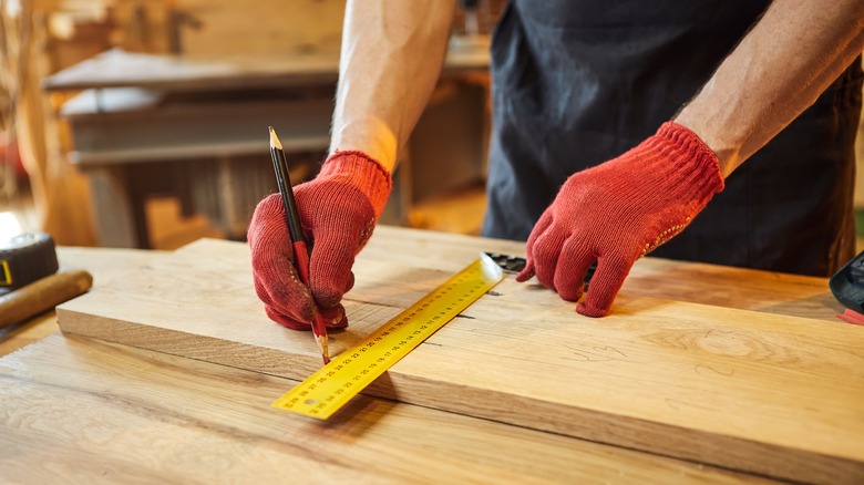 man measuring wood to cut