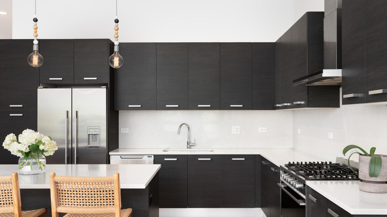 Dark cabinets in a kitchen with white backsplash and countertops