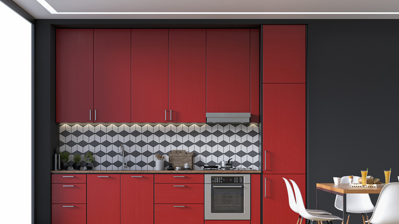 Red cabinets in a kitchen with a checkered backsplash