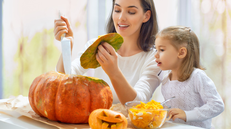 Mom and daughter carving pumpkin