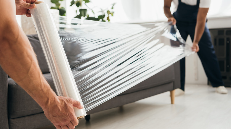 two people unroll plastic wrap