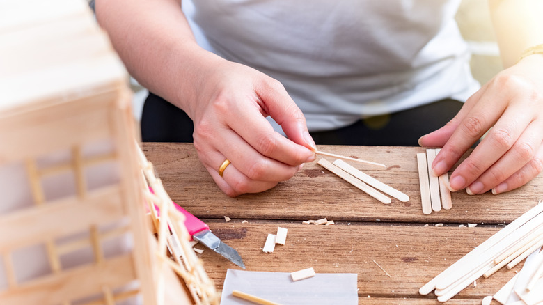 Someone using popsicle sticks to create a DIY