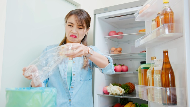 Woman removing spoiled food from fridge