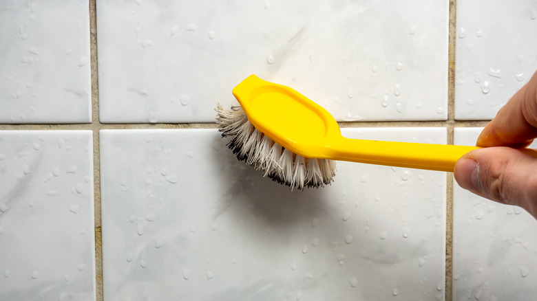 person cleaning grout with toothbrush