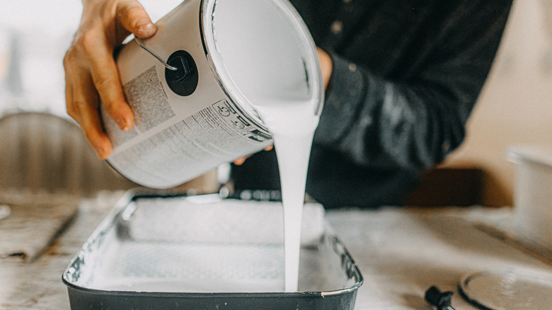 Person pouring primer into a paint pan