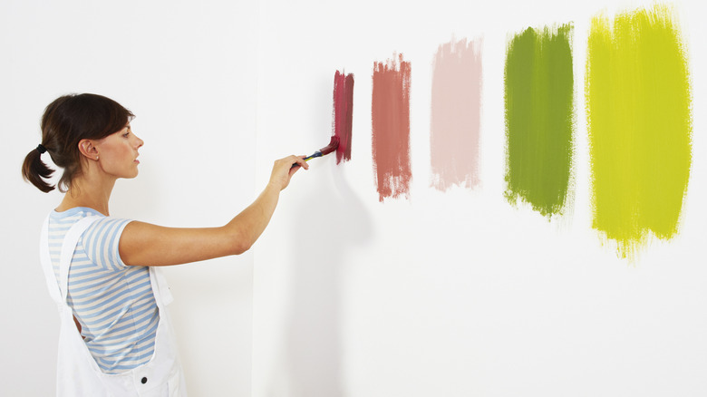 woman sampling paint on wall