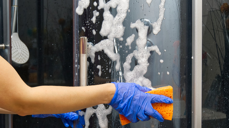 Gloved hand cleans shower door