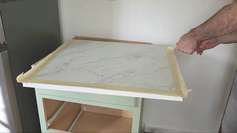 A man peeling tape off a piece of laminate