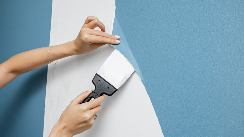 person removing wallpaper with scraper