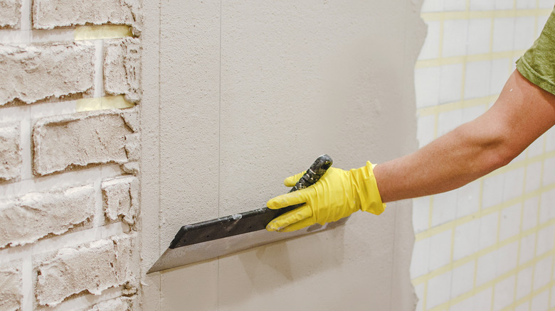 person adding plaster to wall