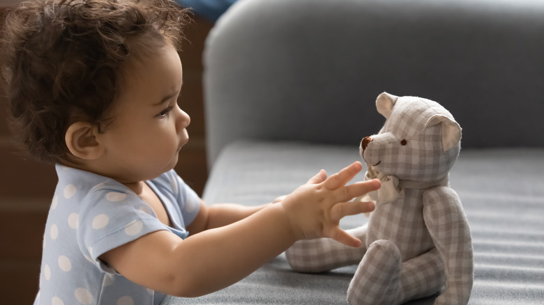 Baby grabs toy from couch