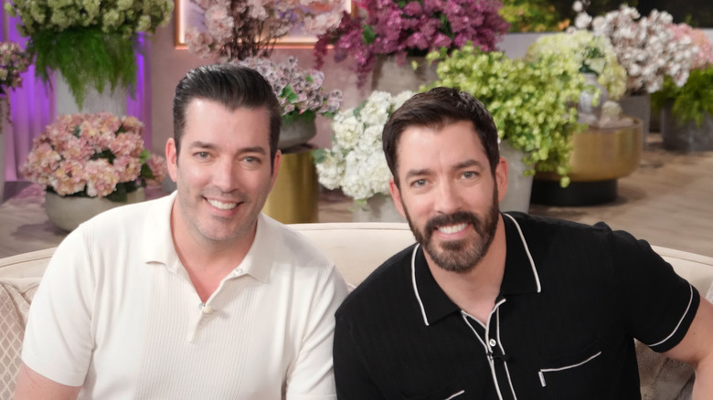 HGTV's Property Brothers smiling in front of floral arrangements